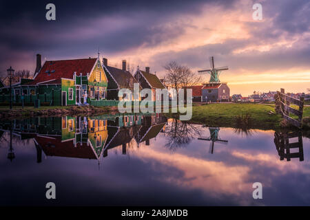 Zaanse Schans traditional windmills in the Netherlands. Beautiful and colorful cloudy evening. Water reflection. Stock Photo
