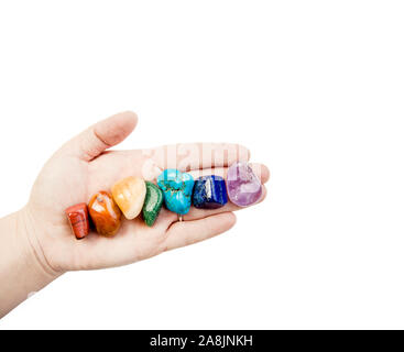 Close up view of woman healer hand showing all seven chakra color crystal stones in color order, isolated on white background. Crystal healer lifestyl Stock Photo