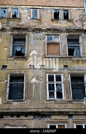 Old Desolate Apartment House With Damaged Facade And Bursted Windows Stock Photo