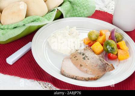 pork roast served with mashed potatoes and brussels sprouts salad  which is made with butternut squash, cherry tomatoes, and spanish onion Stock Photo