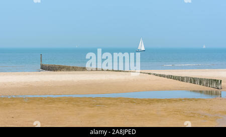 Beach of the North, Belgium, with a sailboat and a cargo boat in background Stock Photo