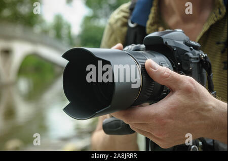 The photographer is focusing. The photographer's hand is turning the focusing ring of the lens. Stock Photo
