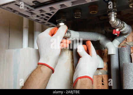The worker is connecting the pipes to a domestic gas boiler. Stock Photo