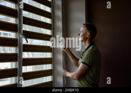 The man is pulling the chain to open the roller blinds. Stock Photo