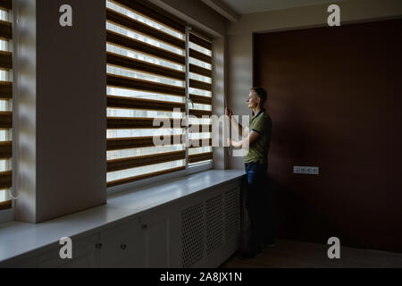 The man is pulling the chain to open the roller blinds. Stock Photo