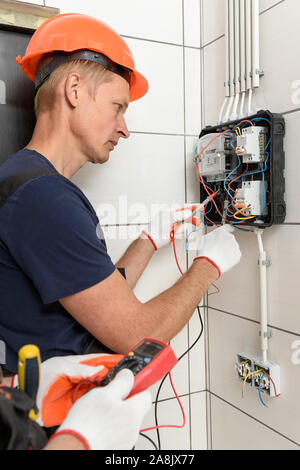 Electricians are checking the voltage at the terminals of the electrical meter. They are using a multimeter. Stock Photo