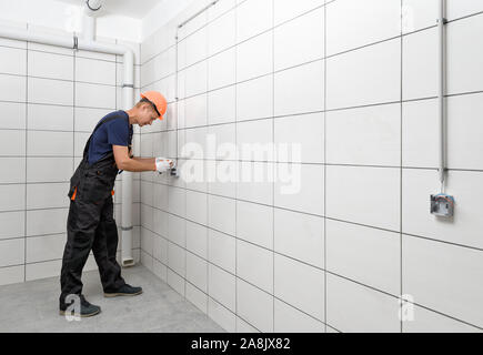The electrician is installing an electrical outlet on the wall. Stock Photo