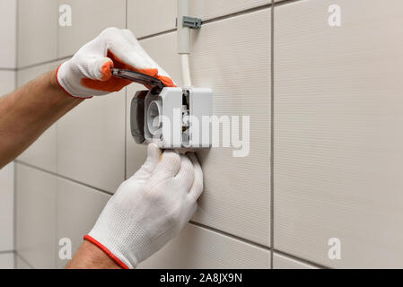 An electrician is installing an electrical outlet on the wall. Stock Photo