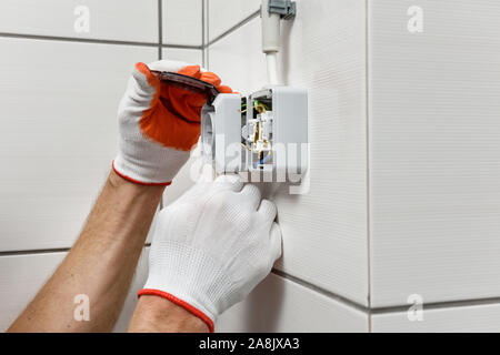 An electrician is installing an electrical outlet on the wall. Stock Photo