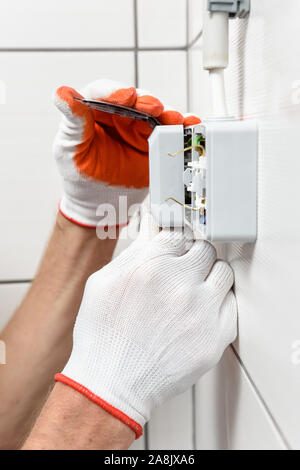 An electrician is installing an electrical outlet on the wall. Stock Photo