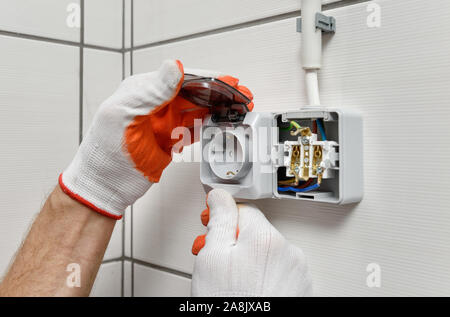 An electrician is installing an electrical outlet on the wall. Stock Photo