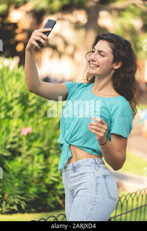 Smiling girl taking a selfie with herself behind of green plants Stock Photo
