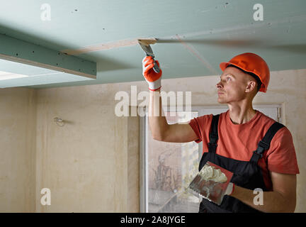 The worker is filling the  plasterboards seams the gypsum putty. Stock Photo