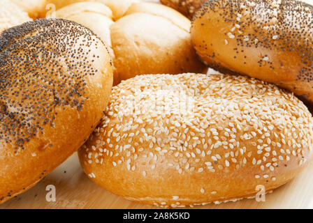 Assorted Kaiser rolls. Some are topped with sesame seeds, some with poppy seeds and a few are plain. Shallow definition of field with selective focus. Stock Photo