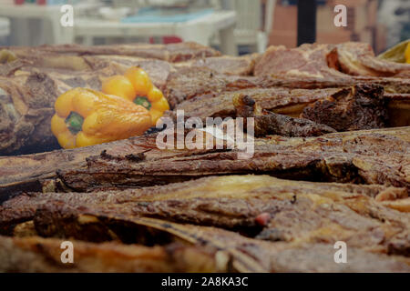 some pieces of tomahawk meat with a yellow pepper on a barbecue grill with smoke Stock Photo