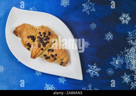 Delicious sweet meal. Golden croissant on a blue winter background. Stock Photo