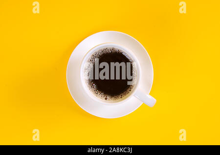 Black coffee in a coffee cup top view isolated on yellow background Stock Photo