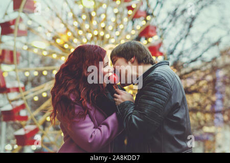 Loving couple in festive Christmas city celebrate the New Year. Romantic walk in winter. Having fun in winter christmas fair market decorations at cen Stock Photo