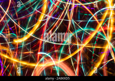 Close-up abstract multicolored chaotic glowing neon stripes on black background. Trendy neon background. Photographic effect with long exposure while Stock Photo