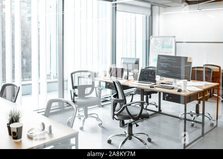 Working places with computers, gadgets and some documents on the table with no people in the modern coworking office Stock Photo