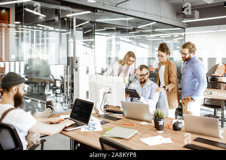 Group of diverse colleagues working on the computers in the modern office or coworking space, bearded hipster as a programmer writing code Stock Photo