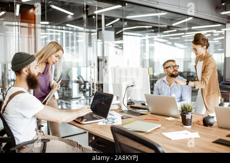 Group of diverse colleagues working on the computers in the modern office or coworking space, bearded hipster as a programmer writing code Stock Photo