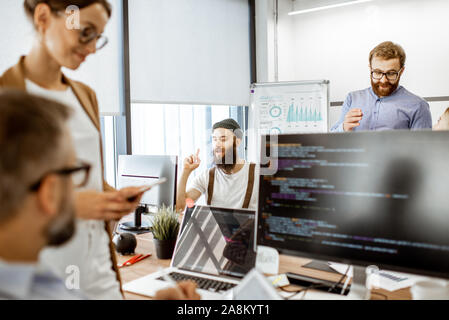 Group of diverse colleagues working on the computers in the modern office or coworking space, bearded hipster having an idea Stock Photo