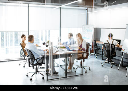 Group of diverse colleagues working on the computers in the modern office or coworking space, wide intreior view Stock Photo