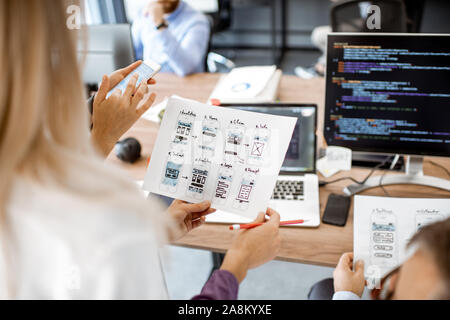 Developers or web designers developing mobile application in the office, close-up on phone and paper sketches Stock Photo
