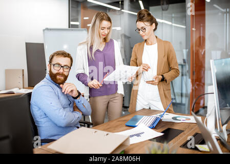 Group of diverse colleagues working in the office, having discussion or small conference at the working place Stock Photo