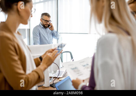 People working in the office, senior manager having a serious conversation on the phone Stock Photo