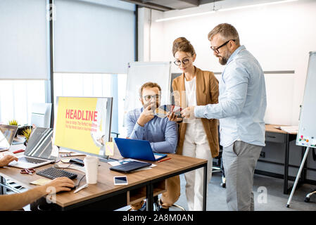 Group of diverse creative people having a small discussion, working as a web designers in the modern office or coworking space Stock Photo