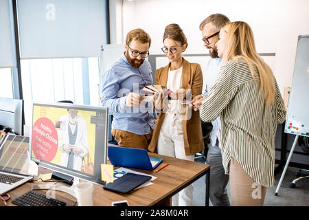 Group of diverse creative people having a small discussion, working as a web designers in the modern office or coworking space Stock Photo