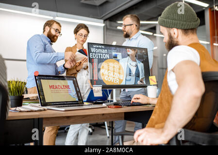 Group of diverse creative people working as a web designers in the modern office, bearded hipster designing cover on the computer Stock Photo