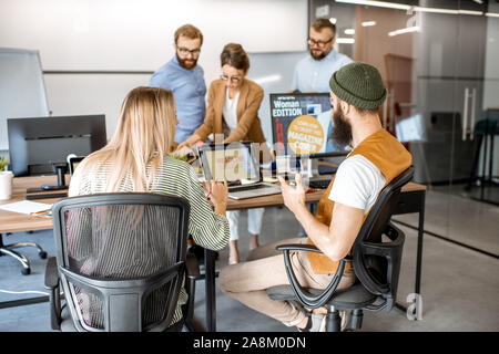 Group of diverse creative people working as a web designers in the modern office, young couple designing on the computer Stock Photo