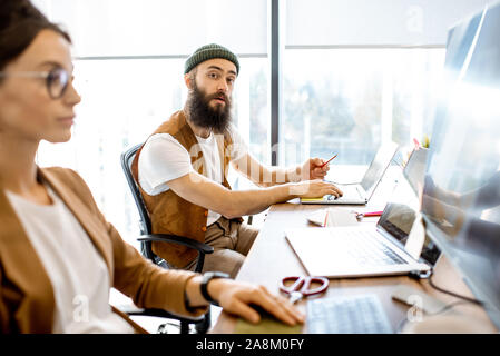Creative young man and woman as a web designers working on the computers in the office or coworking space Stock Photo