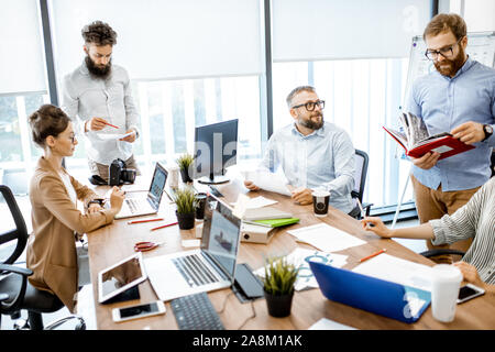 Group of diverse colleagues working in the modern office, having discussion or small conference on a working place with computers Stock Photo