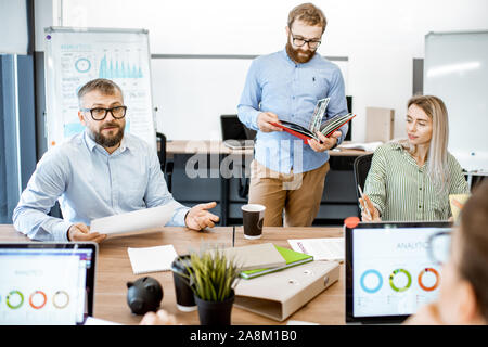 Group of diverse colleagues working in the modern office, having discussion or small conference on a working place with computers Stock Photo