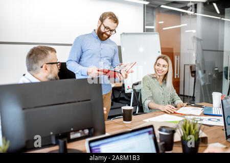 Group of diverse colleagues working in the modern office, having discussion or small conference on a working place with computers Stock Photo