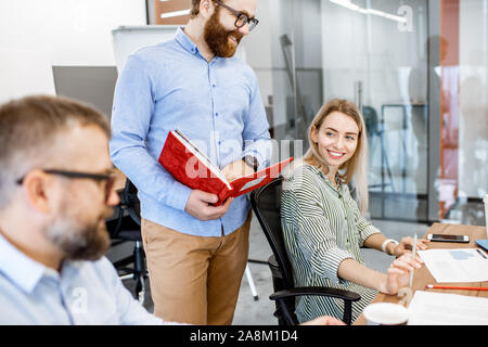 Young colleagues working in the office, having discussion on a working place with computers Stock Photo