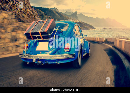 Retro car with luggage on the roof rack on the coastal road. Travel, vacation concepts.retro, vintage color Stock Photo