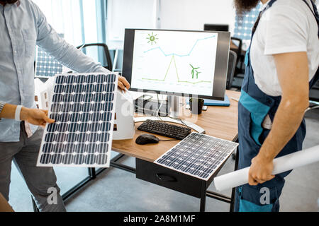People working on a project of alternative energy, working with house model and computer in the office, close-up on the working place Stock Photo
