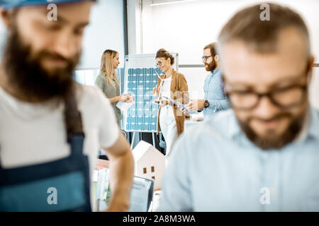 Group of people working on a project of alternative energy in the office, foreman and builder on the foreground Stock Photo