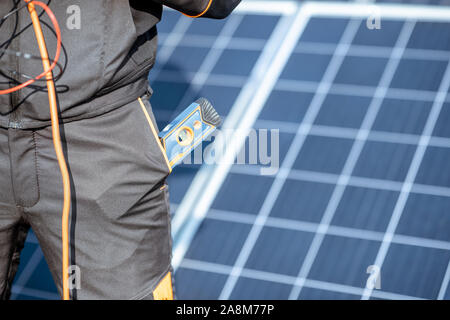 Close-up on a working tools in the pocket of a workman with a solar panels on the background Stock Photo