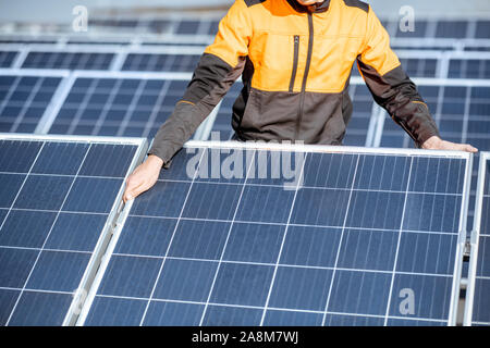 Workman installing or replacing solar panel on a photovoltaic rooftop plant, close-up Concept of maintenance and installation of solar stations Stock Photo
