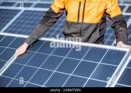 Workman installing or replacing solar panel on a photovoltaic rooftop plant, close-up Concept of maintenance and installation of solar stations Stock Photo