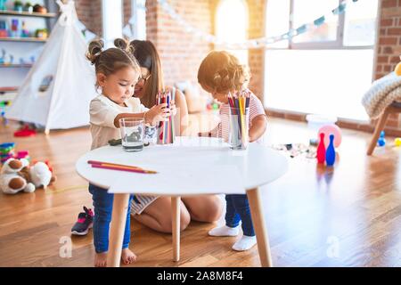 Young beautiful teacher and toddlers playing at kindergarten Stock Photo