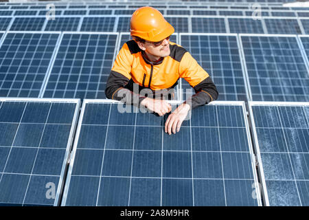 Portrait of a handsome engineer or workman in protective orange workwear standing on a photovoltaic power plant Stock Photo