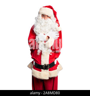 Middle age handsome man wearing Santa Claus costume and beard standing shaking and freezing for winter cold with sad and shock expression on face Stock Photo