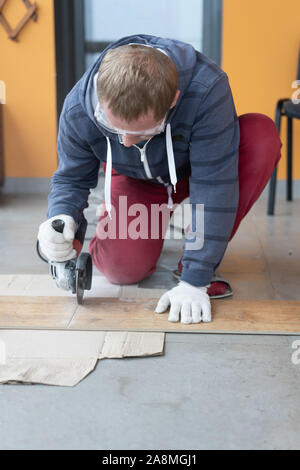 repair and decoration. a man cuts ceramic tiles with a grinder. Stock Photo